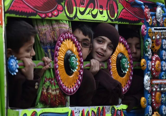 Pakistani children travel to school in a van in Peshawar on January 12, 2015. Schools in Pakistan's northwestern city of Peshawar re-opened on January 12 for the first time since a Taliban raid massacred 150 people, mainly children, with returning students expressing defiance tinged with apprehension. (Photo by A. Majeed/AFP Photo)