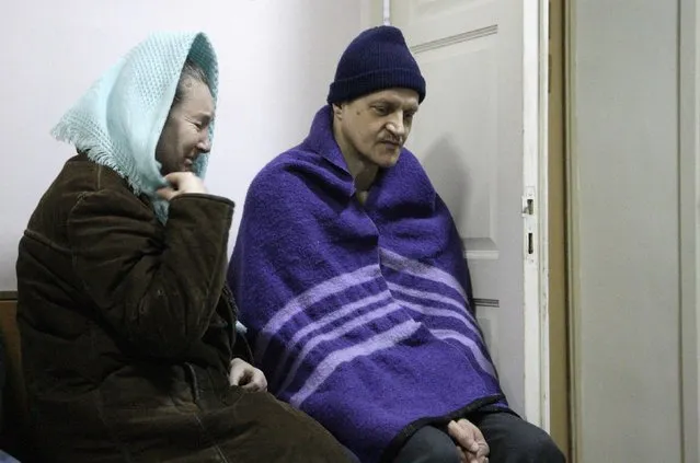 A woman reacts while sitting near a man, taking cover with a blanket, at a hospital in Donetsk, eastern Ukraine, January 26, 2015. (Photo by Alexander Ermochenko/Reuters)