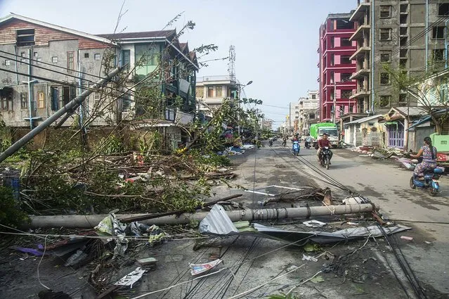 Locals ride motorbike while lamp-posts and trees are fallen after Cyclone Mocha in Sittwe township, Rakhine State, Myanmar, Monday, May 15, 2023. (Photo by AP Photo/Stringer)
