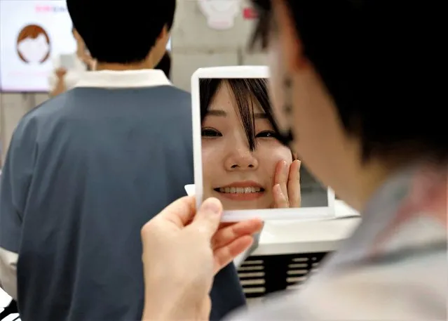 A student practices smiling with a mirror at a smile training course at Sokei Art School in Tokyo, Japan on May 30, 2023. (Photo by Kim Kyung-Hoon/Reuters)