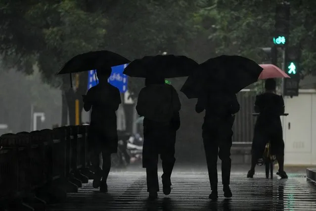 People use umbrellas to protect themselves from rainfall brought about by tropical storm as they walk through an underneath highway in Beijing, Tuesday, August 1, 2023. Days of unusually heavy rains around China's capital, Beijing, have flooded houses, torn apart roads and left more than dozen people dead and missing, state media reported Tuesday. (Photo by Andy Wong/AP Photo)