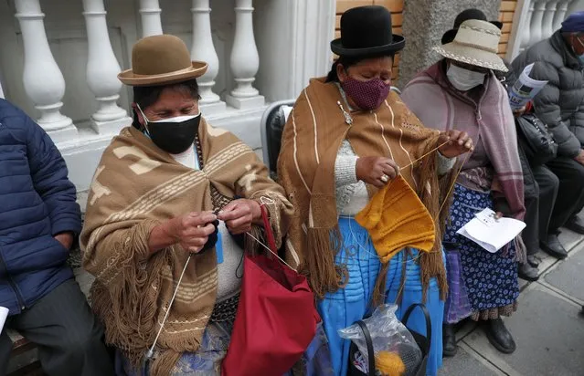 Women knit while waiting for their shot of the AstraZeneca vaccine for COVID-19 at a government-run social security clinic during vaccinations for people over age 80 in La Paz, Bolivia, Wednesday, April 14, 2021. (Photo by Juan Karita/AP Photo)