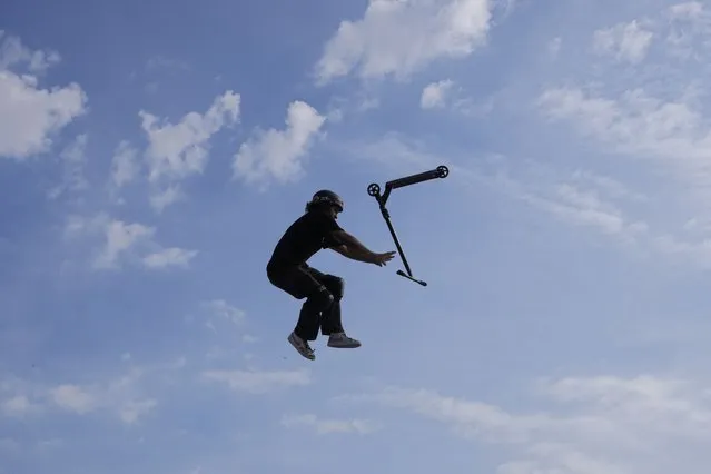 A participant lets go of his scooter while performing acrobatics during an international Urban Sports event in Madrid, Spain, Sunday, June 18, 2023. (Photo by Paul White/AP Photo)