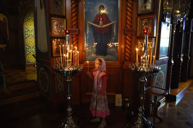 A child lights a candle during a Christmas Eve service at the Protection of the Holy Virgin Russian Orthodox Church in Sydney, Australia, 06 January 2016. The majority of the Orthodox churches worldwide celebrate Christmas on January 7, adopting the Julian calendar created under the reign of Julius Caesar in 45 BCE, electing not to use the Gregorian calendar as other Christian denominations do. (Photo by Mick Tsikas/EPA)