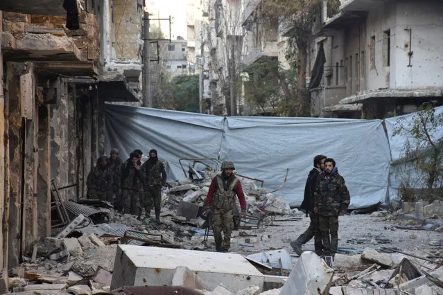 Syrian government soldiers walk amid rubble of damaged buildings, near a cloth used as a cover from snipers, after they took control of al-Sakhour neighborhood in Aleppo, Syria in this handout picture provided by SANA on November 28, 2016. (Photo by Reuters/SANA)