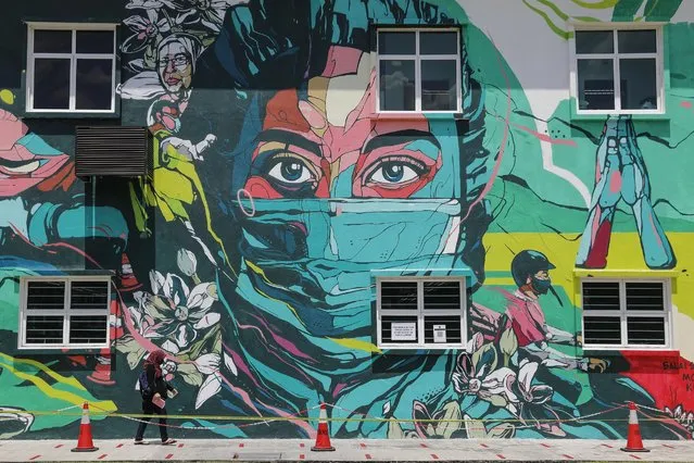 A woman walks in front of a mural depicting  a healthcare worker at government clinic in Kuala Lumpur, Malaysia, 15 March 2021. Human Rights Watch on 14 March called on Malaysian government to revoke its “fake news” ordinance that “poses a serious threat to freedom of expression and privacy and the right to a fair trial”. The new ordinance makes it a criminal offense to create, publish, or disseminate “fake news” relating to COVID-19 or the proclamation of emergency in the country, or to fail to take down such material upon the government's request. (Photo by Fazry Ismail/EPA/EFE)