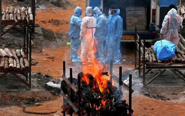 Relatives perform the last rites for COVID-19 victims during their funeral at a mass cremation ground in Giddenahalli on the outskirts of Bangalore, India, 03 May 2021 (issued 04 May 29021). India recorded a massive surge of 357,229 fresh COVID-19 cases and 3,449 deaths in the last 24 hours. (Photo by Jagadeesh N.V./EPA/EFE)