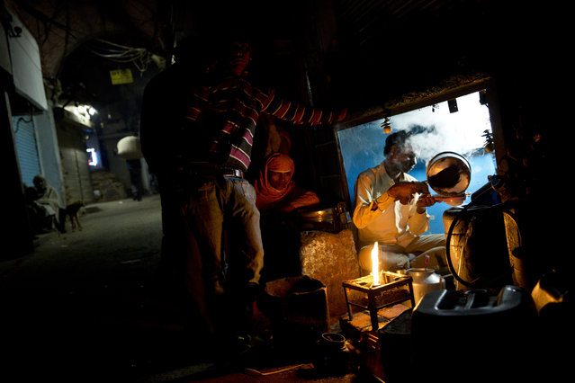 A tea seller prepares tea for laborers in the old city area of New Delhi, India, Wednesday, February 11, 2015. India is the second largest tea producer in the world and the drink is the most popular hot beverage in the country. Tea production declined across the country in 2014, according to the Tea Board of India. (Photo by Bernat Armangue/AP Photo)