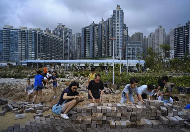 People clean up debris caused by Typhoon Mangkhut outside a housing estate on the waterfront in Hong Kong, Monday, September 17, 2018. Hong Kong and southern China hunkered down as strong winds and heavy rain from Typhoon Mangkhut lash the densely populated coast. The biggest storm of the year left at least 28 dead from landslides and drownings as it sliced through the northern Philippines. (Photo by Vincent Yu/AP Photo)