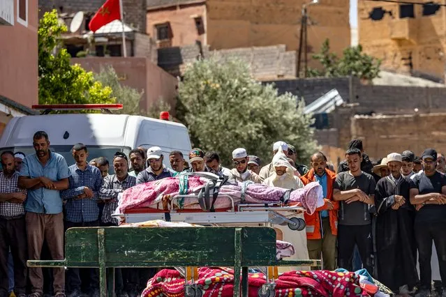 People recite a prayer in front of the bodies of victims killed in an earthquake in Moulay Brahim, Al Haouz province, on September 9, 2023. (Photo by Fadel Senna/AFP Photo)