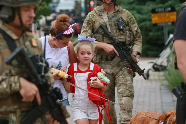 Law enforcement escorts a family away from the scene of a shooting at a Fourth of July parade on July 4, 2022 in Highland Park, Illinois. Police have detained Robert “Bobby” E. Crimo III, 22, in connection with the shooting in which six people were killed and 19 injured, according to published reports.  (Photo by Mark Borenstein/Getty Images)