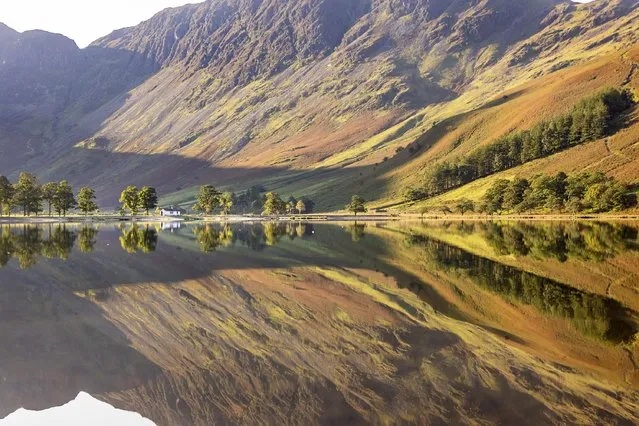 A little white hut on the shore of Buttermere in Cumbria, UK is reflected on the calm water’s surface early September 2023. (Photo by Andrew McCaren/London News Pictures)
