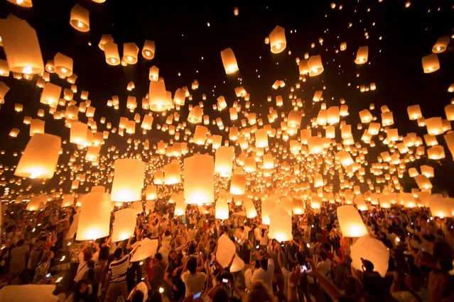 In this photo taken Saturday, November 16, 2013,  thousands of paper-made balloons, powered by burning oil, rise into the evening sky in Chiang Mai province, some 580 kilometers (360 miles) north of Bangkok during the Loy Krathong Festival. During the festival at night time,  Thais float lanterns to the sky and float candles on the lotus-shaped basket into the rivers, in order to drift away their bad luck. (Photo by Vincent Thian/AP Photo)