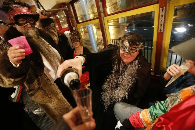 Members of the “Societe des Champs Elysee” riding the Rampart-St. Claude street car line, which just opened last fall, pour champagne to commemorate the official start of Mardi Gras season, in New Orleans, Friday, January 6, 2017. (Photo by Gerald Herbert/AP Photo)
