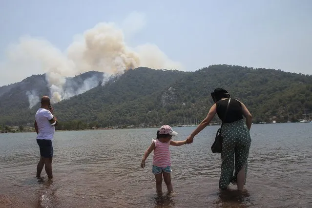 People watch a wildfire burning the forest in Turgut village, near tourist resort of Marmaris, Mugla, Turkey, Wednesday, August 4, 2021. (Photo by Emre Tazegul/AP Photo)