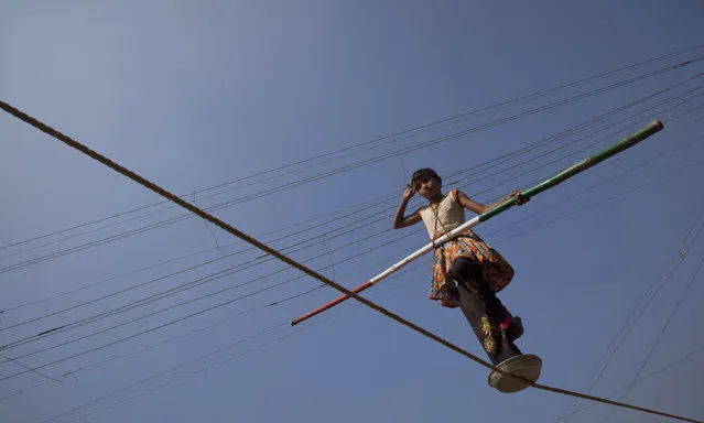 A 10-year-old tightrope walker balances herself on a rope with her feet inside an aluminium tin as she performs for a crowd in the village of Masur, 325km (202 miles) south of Mumbai, December 5, 2011. (Photo by Vivek Prakash/Reuters)