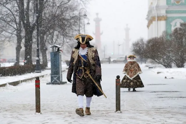 Street actors walk during a snowfall in St. Petersburg, Russia, 27 November 2023. The temperatures have reached minus three degrees Celsius in the second-largest city of Russia. (Photo by Anatoly Maltsev/EPA/EFE)