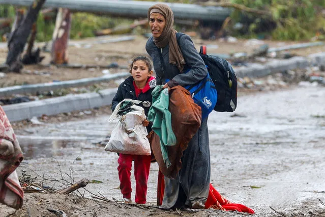 A barefooted Palestinian woman fleeing north Gaza with her daughter during rainfall moves southward amid a temporary truce between Israel and Hamas, near Gaza City on November 27, 2023. (Photo by Ibraheem Abu Mustafa/Reuters)