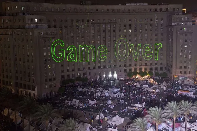 Egyptian protesters calling for the ouster of President Mohamed Morsi gather in Cairo's landmark Tahrir Square on July 2, 2013 as laser lights (L) directed at the government building spell “Game Over”. (Photo by Khaled Desouki/AFP Photo)