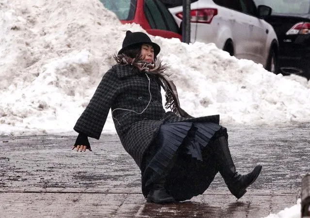 A woman falls while slipping on ice during freezing rain on Roosevelt Island, a borough of Manhattan, in New York January 5, 2014. New York City was hit on Friday by the first severe winter storm of 2014 and was still in the grip of sub-freezing weather on Sunday morning. The woman got up and walked away from the fall. (Photo by Zoran Milich/Reuters)