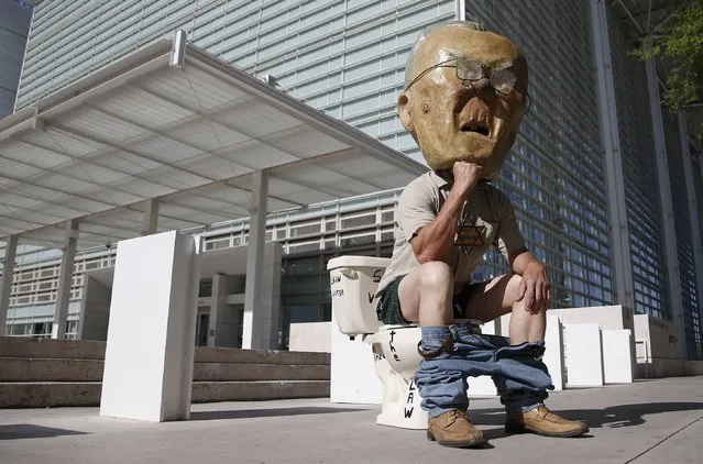 An opponent of Maricopa County Sheriff Joe Arpaio, Jorge Mendez, of Glendale, Ariz., wears an Arpaio mask as he sits on a toilet while protesting in front of U.S. District Court Tuesday, April 21, 2015, in Phoenix.  Arpaio is in a federal courtroom starting for a four-day trial to decide whether he should be held in contempt of court for ignoring a judge's orders and destroying and withholding evidence in a racial-profiling lawsuit. (Photo by Ross D. Franklin/AP Photo)