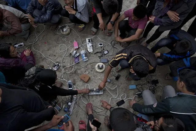 Nepalese villagers charge their cell phones in an open area in Kathmandu, Nepal, Monday, April 27, 2015. (Photo by Bernat Armangue/AP Photo)