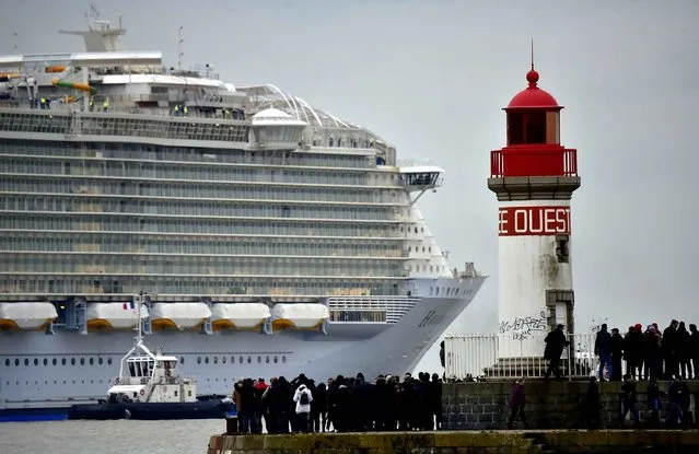People look at the Harmony of the Seas cruise ship leaving the STX shipyard of Saint-Nazaire, western France, for a three-day test offshore, on March 10, 2016. With a capacity of 6.296 passengers and 2.384 crew members, the Harmony of the Seas, built by STX France for the Royal Caribbean International, is the world's largest ship cruise. (Photo by Loic Venance/AFP Photo)