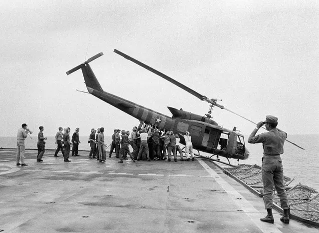 In this Tuesday, April 29, 1975 file photo, U.S. Navy personnel aboard the USS Blue Ridge push a helicopter into the sea off the coast of Vietnam in order to make room for more evacuation flights from Saigon. The helicopter had carried Vietnamese people fleeing Saigon as North Vietnamese forces closed in on the capital. (Photo by AP Photo)