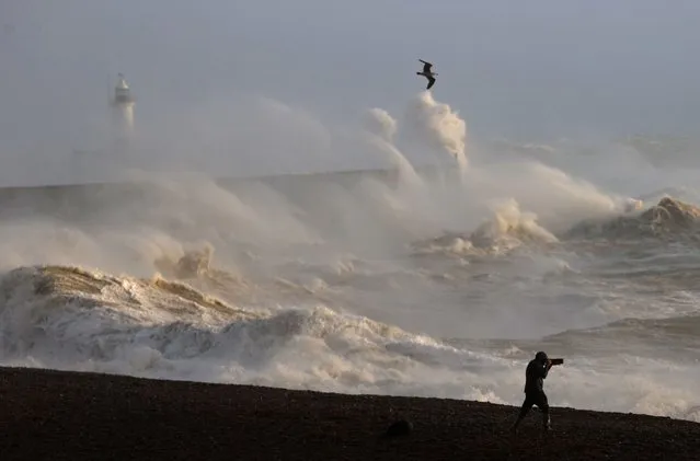A person takes photographs of the sea as waves crash against the breakwater in Newhaven on January 2, 2024, as Storm Henk was set to bring strong winds and heavy rain across much of southern England. (Photo by Adrian Dennis/AFP Photo)
