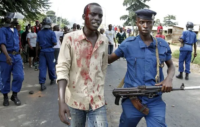 A riot policeman escorts an injured protester who was hit during clashes with riot police against the decision made by Burundi's ruling National Council for the Defence of Democracy-Forces for the Defence of Democracy (CNDD-FDD) party to allow President Pierre Nkurunziza to run for a third five-year term in office, in the capital Bujumbura, April 27, 2015. (Photo by Thomas Mukoya/Reuters)