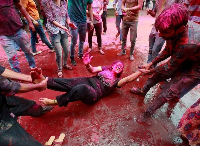 A student reacts as she lies in a road while coloured powder is thrown on her during Holi celebrations at a university campus in Chandigarh, India, March 20, 2019. (Photo by Ajay Verma/Reuters)