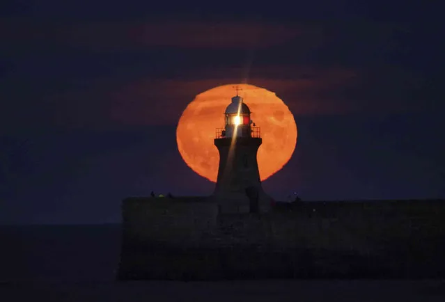 A Harvest Moon rises over South Shields lighthouse on the north east coast of England, Monday, September 20, 2021. (Photo by Owen Humphreys/PA Wire via AP Photo)