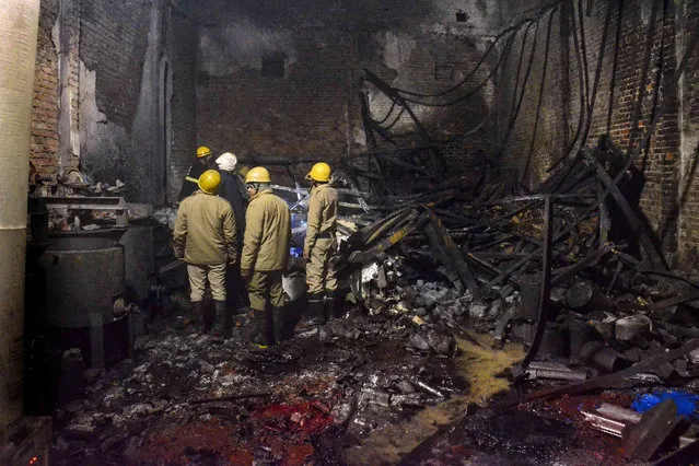 Fire brigade personnel look on after dousing a late Thursday fire at a paint factory in the Alipur area in northern New Delhi, India, Friday, February 16, 2024. Charred bodies of 11 unidentified victims were recovered from the rubble. The cause of the fire was not immediately clear. (Photo by AP Photo)