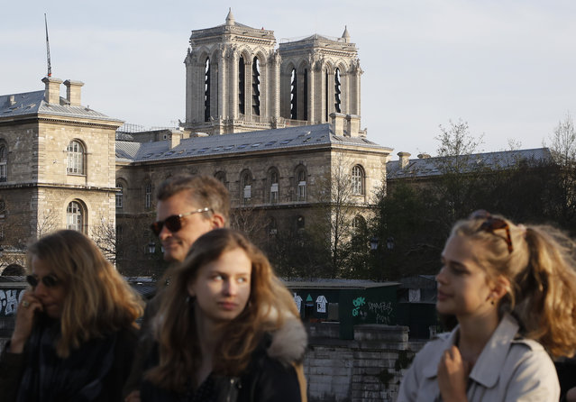 The Notre Dame Cathedral is seen as people crosse the Change bridge in Paris, Wednesday, April 17, 2019. Notre Dame Cathedral would have been completely burned to the ground in a “chain reaction collapse” had firefighters not moved rapidly in deploying their equipment to battle the blaze racing through the landmark monument, a Paris official said Wednesday. (Photo by Michel Euler/AP Photo)