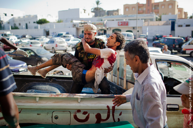 A Libyan Rebel soldier unloads a wounded fellow fighter for medical attention to the Tripoli Central Hospital
