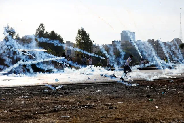 A man runs as Palestinians clash with Israeli troops during a protest near the Jewish settlement of Beit El, near Ramallah, in the Israeli-occupied West Bank on November 11, 2021. (Photo by Mohamad Torokman/Reuters)