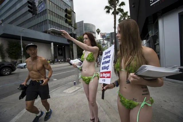 Activists from People for the Ethical Treatment of Animals (PETA) hold signs promoting a vegan diet as a man jogs past in Los Angeles, California May 21, 2015. (Photo by Mario Anzuoni/Reuters)