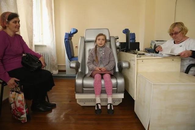 Oksana Kurkach, 8, sits in a chair lined with instruments that will analyze her for radiation emitted from caesium-137, at the National Research Center for Radiation Medicine, April 7, 2016, in Kiev, Ukraine. Thousands of people in Ukraine live in regions still contaminated to varying degrees with radiation from the 1986 meltdown of reactor four at the Chernobyl nuclear power plant. (Photo by Sean Gallup/Getty Images)