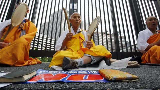 Buddhist monks beat drum and chant a mantra during a rally in Tokyo, Sunday, May 24, 2015. About 15,000 protesters formed a human chain around the parliament against a new U.S. base construction in Henoko, Okinawa prefecture. (Photo by Shizuo Kambayashi/AP Photo)