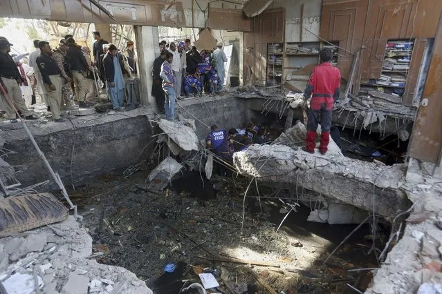 Rescuers inspect the scene of a gas explosion in Karachi, Pakistan, Saturday, December 18, 2021. The powerful gas explosion in a sewage system in the southern Pakistan city killing several people and wounding others Saturday, police and a health official said. (Photo by Fareed Khan/AP Photo)