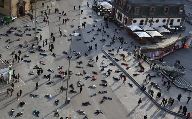 People lay down in a pedestrian zone as part of an art project in remembrance of the 528 victims of the “Katzbach” Nazi concentration camp, in Frankfurt, March 24, 2014. The inmates of the Katzbach concentration camp, a part of the former Adler industrial factory, were forced into a death march to the concentration camps of Buchenwald and Dachau on March 24th 1945.  Some 528 victims of Katzbach are buried at Frankfurt's central cemetery. (Photo by Kai Pfaffenbach/Reuters)