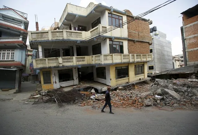 A man walks past a damaged and collapsed five-storey house, a month after the April 25 earthquake in Kathmandu, Nepal May 25, 2015. (Photo by Navesh Chitrakar/Reuters)