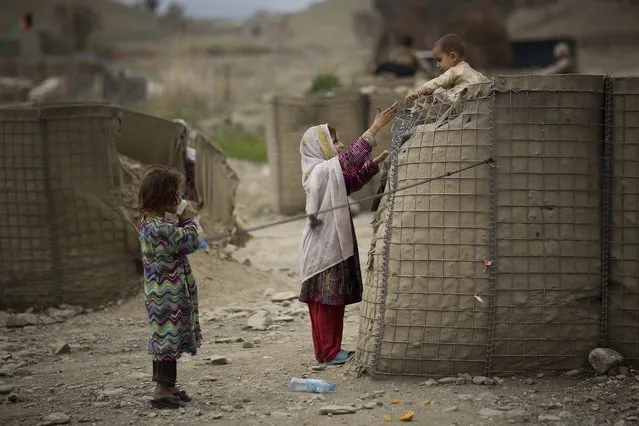 An Afghan girl helps her brother down from a security barrier set up outside the Independent Election Commission (IEC) office in the eastern Afghan city of Khost, Thursday, April 3, 2014. (Photo by Anja Niedringhaus/AP Photo)