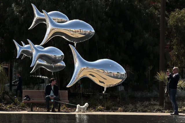 A man takes a photo of fish-shaped balloons floating above water fountains in Nice, France, to mark April Fools Day, or “Poisson d’Avril”, on April 1, 2014. (Photo by Eric Gaillard/Reuters)