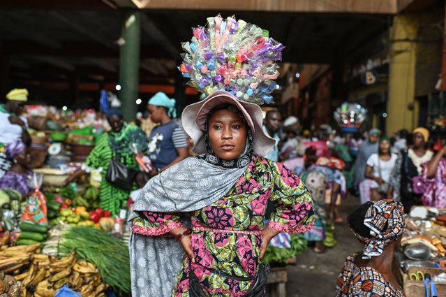Massangbe Doumbia, 25, a street vendor, carries goods on her head at the Adjame main market in Abidjan, Ivory Coast on March 7, 2024. (Photo by Issouf Sanogo/AFP Photo)