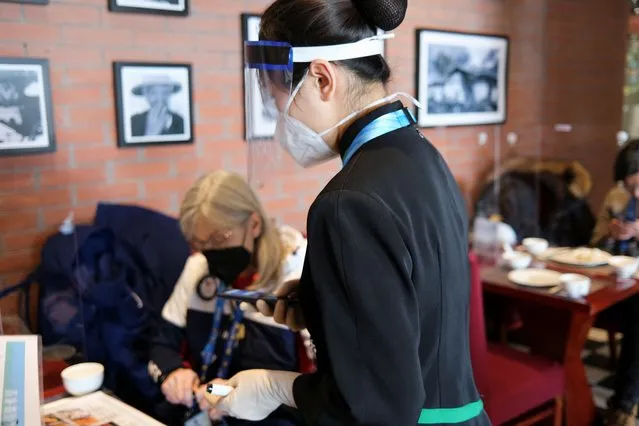 A Chinese server uses a translation device to communicate with a foreign guest at the Green Dragon restaurant inside the Olympics closed loop in Zhangjiakou, China, February 14, 2022. (Photo by Yiming Woo/Reuters)