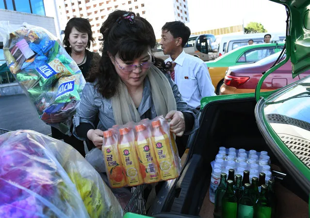 Patrons of the Kwangbok (which means revolution) department / grocery store load plastic flowers and food into their trunk in  Pyongyang, North Korea on May 4, 2016. The items will likely be used in the upcoming Workers' Party festivities celebrating the seventh congress in their nation's history. The last such event was held in 1980. (Photo by Linda Davidson/The Washington Post)