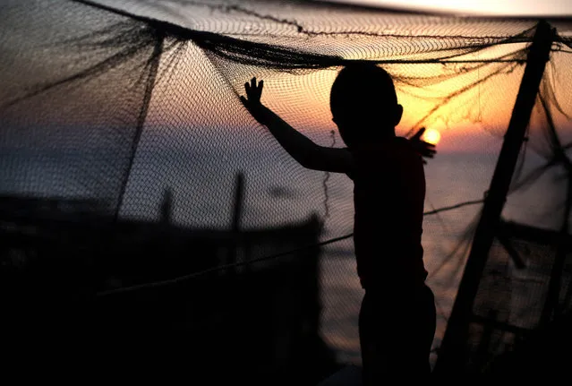 A Palestinian child plays with a fishing net as the sun sets over Gaza City on April 28, 2014. (Photo by Mohammed Abed/AFP Photo)