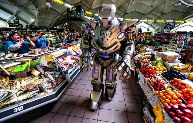 Employees of a food stand take pictures of Titan, a robot created by England Cyberstein Robots, performing at the Danilovsly market in downtown of Moscow, Russia, 12 May 2014. (Photo by Sergei Ilnitsky/EPA)