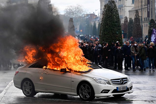 Flames rise from a Mercedes car set on fire during a demonstration on the 12th day of action after the government pushed a pensions reform through parliament without a vote, using the article 49.3 of the constitution, in Rennes, northwestern France on April 13, 2023. France faced nationwide protests and strikes on April 13, 2023, to denounce the French government's pension reform on the eve of a ruling from France's Constitutional Council on the reform. (Photo by Damien Meyer/AFP Photo)